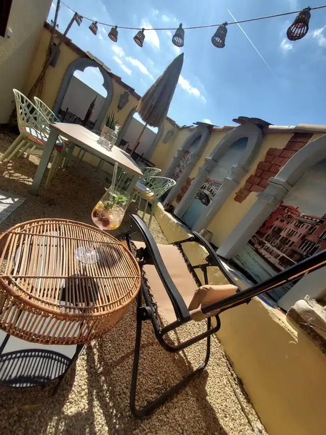 Innenhof mit Wandgestaltung im Stil venezianischer Bögen, Lichterkette und Sitzplatz