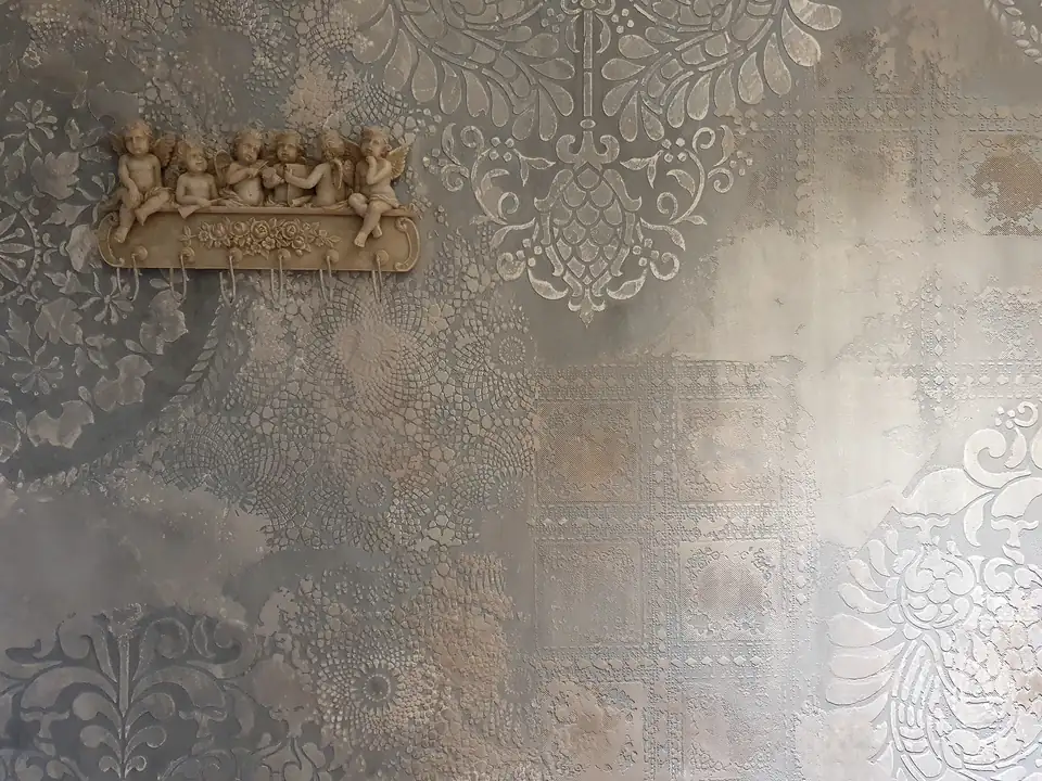 Silbergraue Wand mit Ornamenten und einem plastischen Figurenrelief