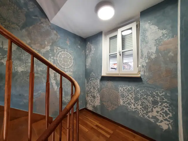 Treppenhaus mit blaugrauer Wandgestaltung und Ornamenten in Schablonentechnik
