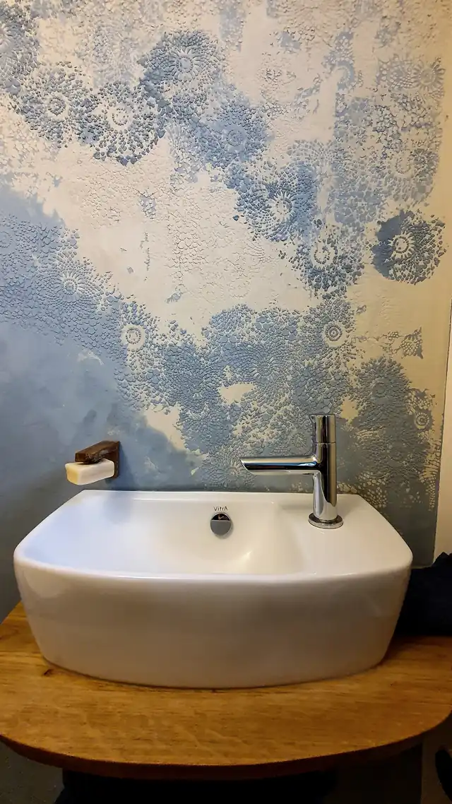 Waschbecken vor einer Wand mit blauem Spitzenmuster