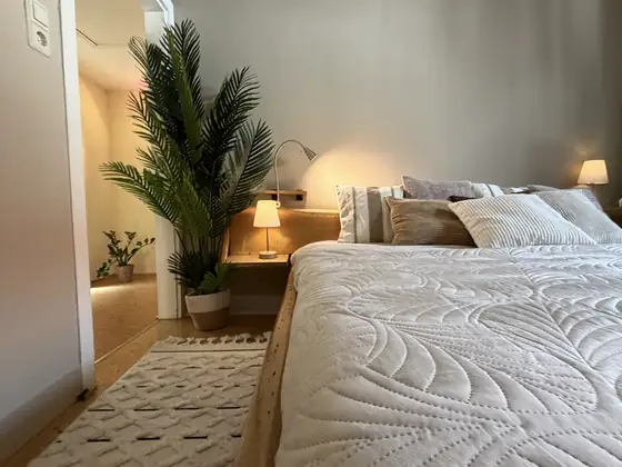 Schlafzimmer nachher in hellen, warmen Tönen mit neuer Bettwäsche und Dekoration
